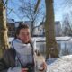 Ichelle staat met een kop koffie en een grote sjaal in het park van Utrecht terwijl er sneeuw ligt.