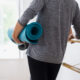 Jeroen in een grijs shirt met een blauwe yoga mat staat in de oefenzaal te wachten